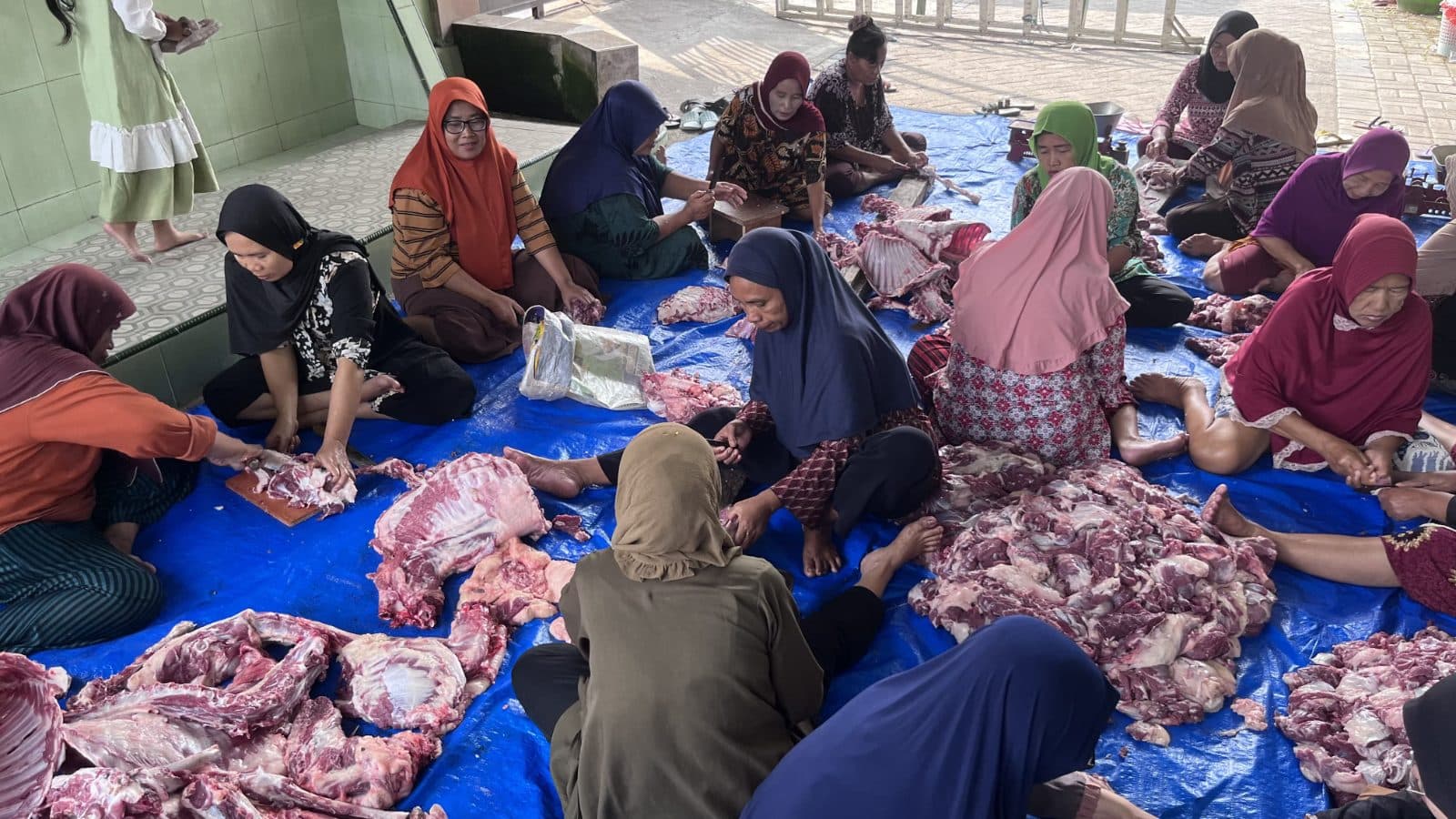 Semangat gotong royong ibu-ibu RW 06 dalam proses pemotongan daging kurban untuk dibagikan kepada warga.